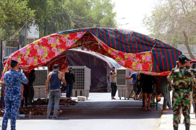 عنصران أمنيان يلتقطان صوراً لمؤيدي الإطار التنسيقي خلال نصبهم خيمة على جسر يؤدي إلى المنطقة الخضراء في بغداد (أ ف ب)