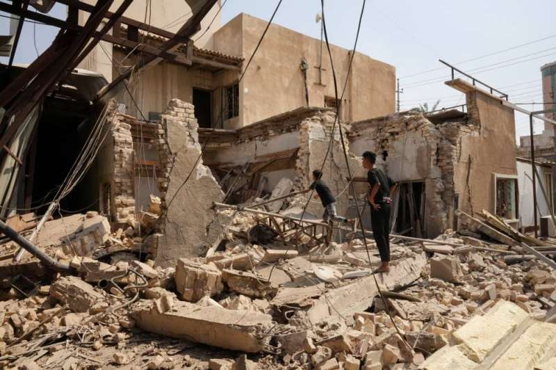 صبيان عراقيان يتفقدان مبنى مدمر لـ«عصائب أهل الحق» في البصرة (رويترز)