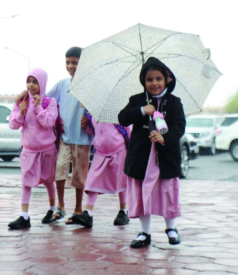 
زهرات يحتمين من المطر في الطريق إلى المدرسة (تصوير سعود سالم)