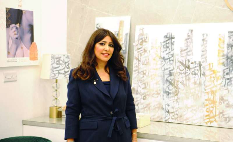 شيماء أشكناني وخلفها مجموعة من لوحاتها 	 (تصوير سعود سالم) 