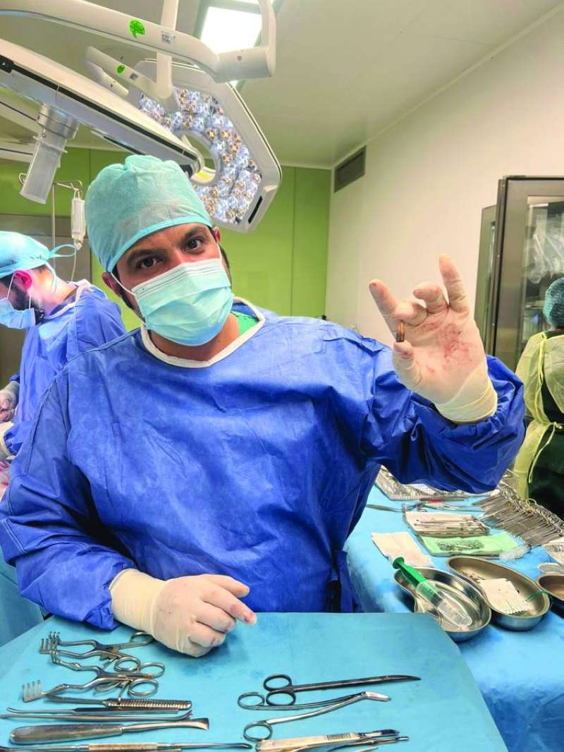 الدكتور حمد العنزي مبرزاً الطلقة التي استخرجها من رأس الطفل