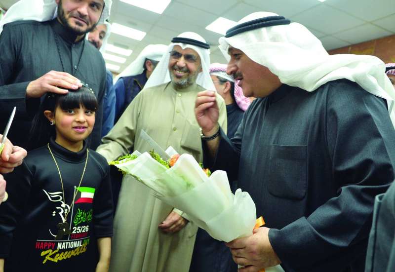 العوضي متسلماً باقة ورود من طفلة 