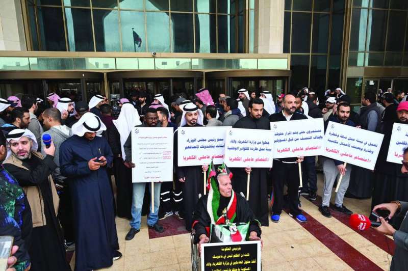 
موظفون يرفعون لافتات تحمل مطالبهم