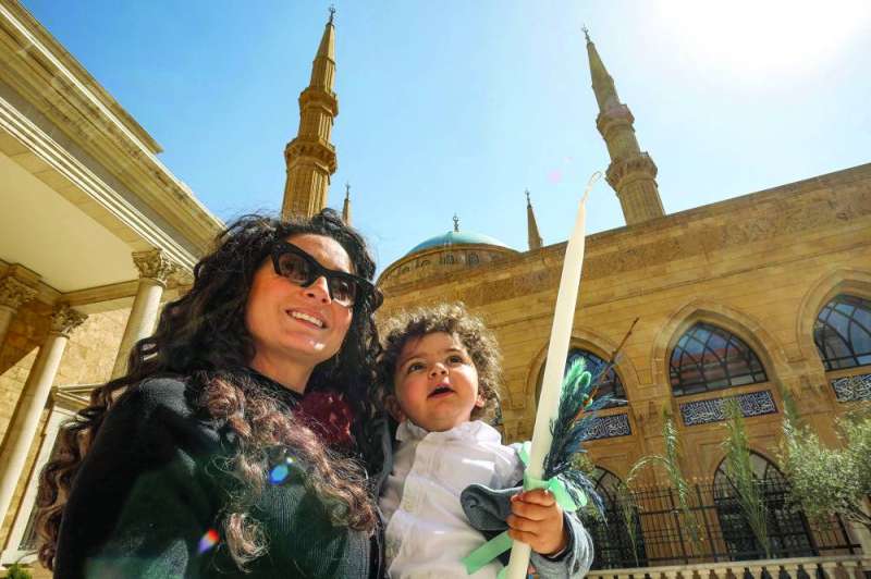 سيدة لبنانية وطفلتها خلال أحد الشعانين في وسط بيروت أمس (أ ف ب)