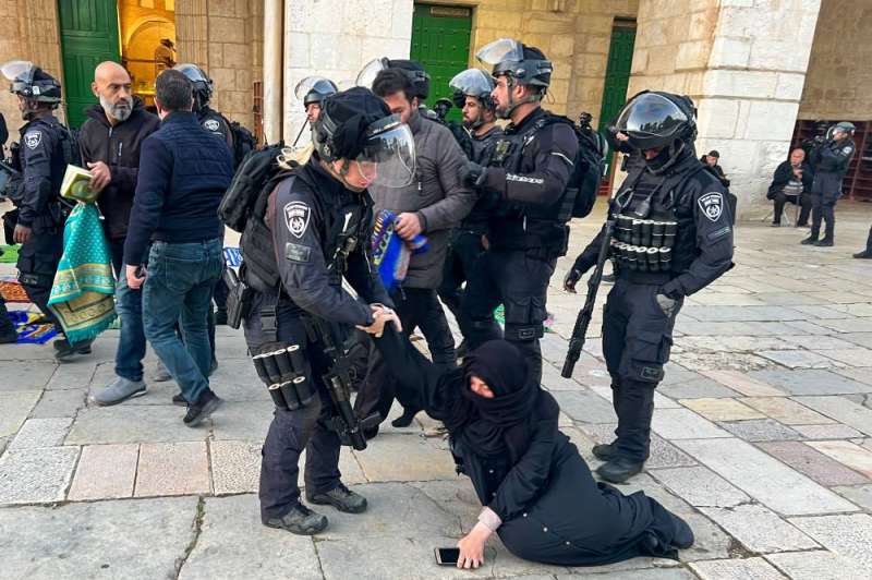 شرطي إسرائيلي يجرّ سيدة فلسطينية كانت تصلي في باحة المسجد الأقصى (أ ف ب)