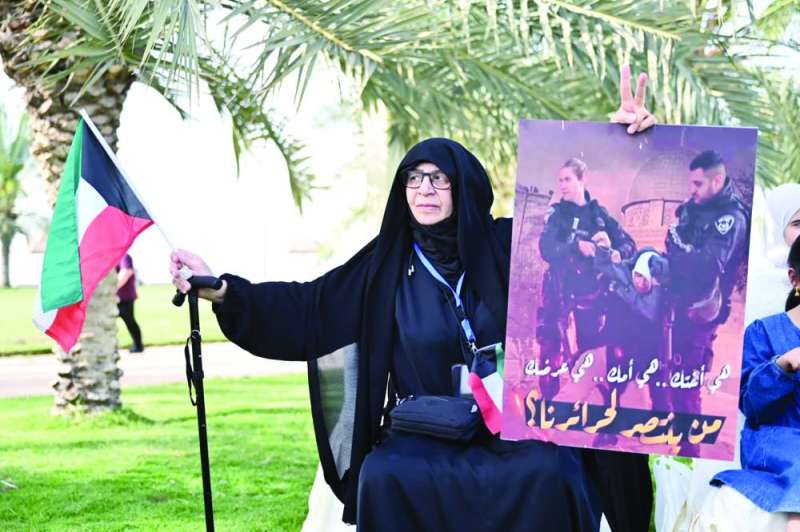 امرأة تحمل صورة لاعتداء قوات الاحتلال على المعتكفات في المسجد الأقصى 	(تصوير أسعد عبدالله)