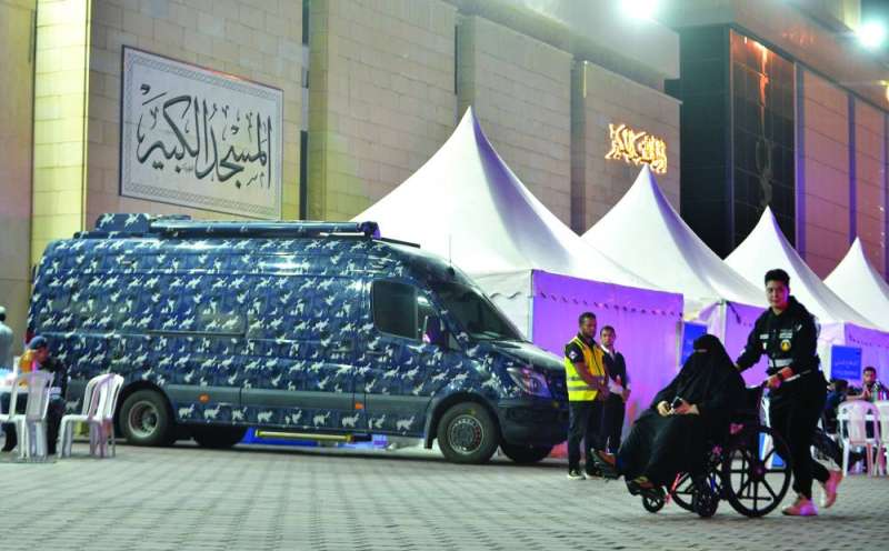 مُتطوّعة تُساعد مُسنّة للوصول إلى المسجد في ظلّ وجود سيارات الأمن