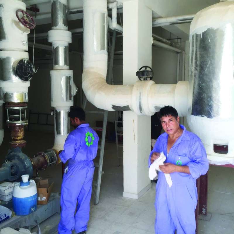 عمال يقومون بصيانة مكائن التكييف في إحدى المدارس