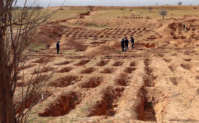 ليبيون حول قبور انتشلت منها جثث في بلدة ترهونة الغربية في 9 فبراير 2022 (أ ف ب) 