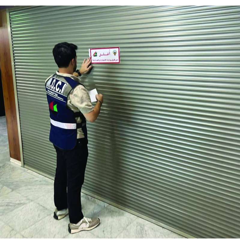 أحد مفتشي «التجارة» يضع ملصق الإغلاق