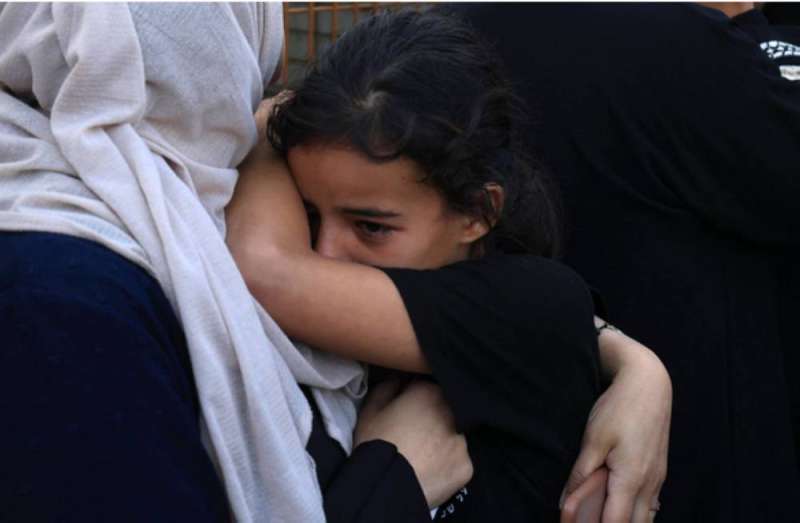 أم فلسطينية تحتضن ابنتها بعد فرارهما من شمال قطاع غزة إلى جنوبه