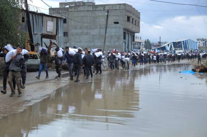 فلسطينيون يحملون أكياس طحين في غزة (رويترز)