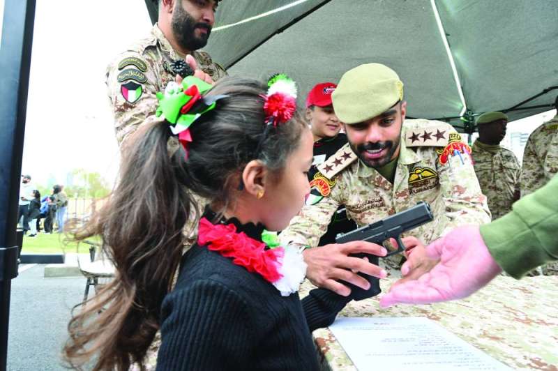 ضابط يساعد طفلة على حمل مسدس في معرض وزارة الدفاع 