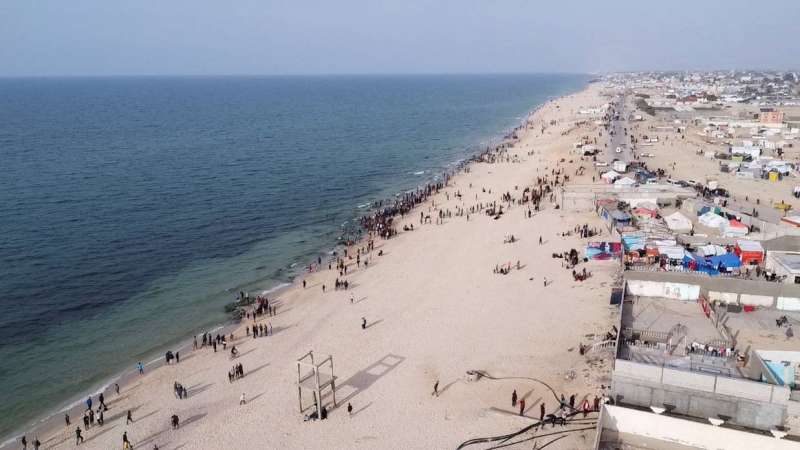 فلسطينيون يتجمعون على شاطئ دير البلح وسط غزة للحصول على مساعدات أردنية تم إسقاطها جواً أمس (رويترز)