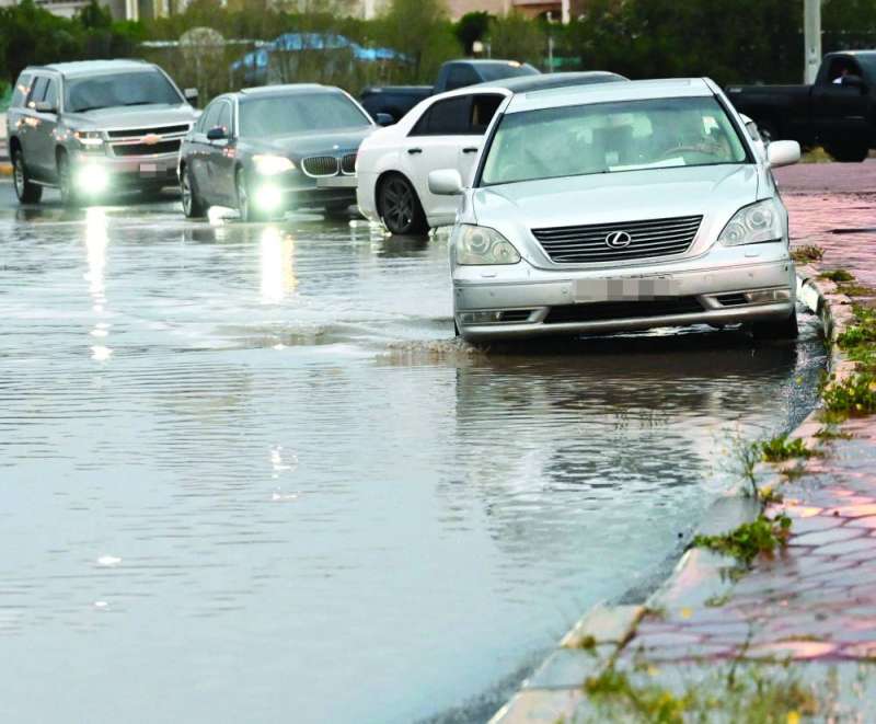 السيارات تسير بحذر على طرف أحد الشوارع التي تجمّعت فيها المياه 