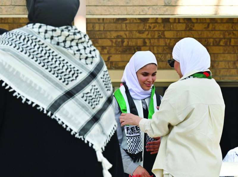 


معلمة تضع الكوفية على كتفي طالبة 	 (تصوير سعود سالم) 