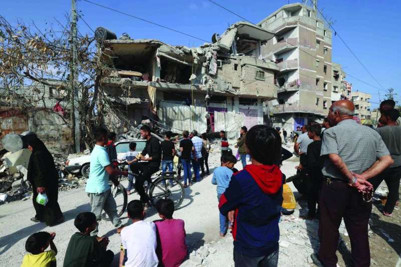 فلسطينيون يعاينون منزلهم المُدمّر بغارة إسرائيلية في رفح (أ ف ب)