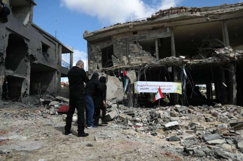 لبنانيون أمام منزل أقارب لهم دمرته غارة إسرائيلية في ميس الجبل (أ ف ب)