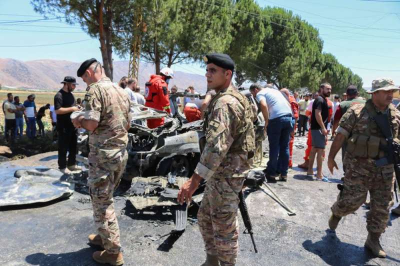 أفراد من أجهزة الطوارئ والأمن وسكان يتجمّعون حول السيارة المستهدفة في بلدة الخيارة أمس (أ ف ب)