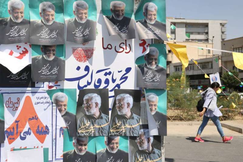 فتاة إيرانية تمر أمام صور المرشح جليلي في طهران (رويترز)