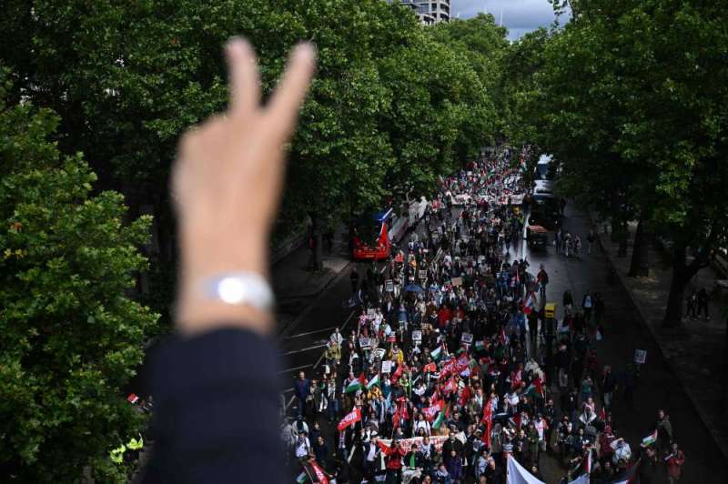متظاهر مؤيد للفلسطينيين يرفع علامة السلام من جسر واترلو بينما يسير المتظاهرون في لندن خلال «المسيرة الوطنية من أجل غزة» مطالبين بـ «إنهاء الإبادة الجماعية» و«وقف تسليح إسرائيل» أمس (أ ف ب)