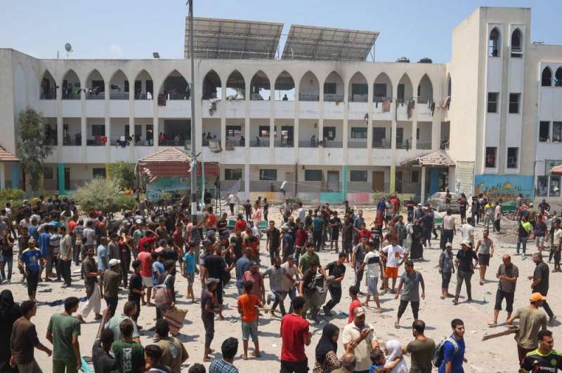 فلسطينيون يتفقّدون موقع مجزرة إسرائيلية في دير البلح أمس (رويترز)