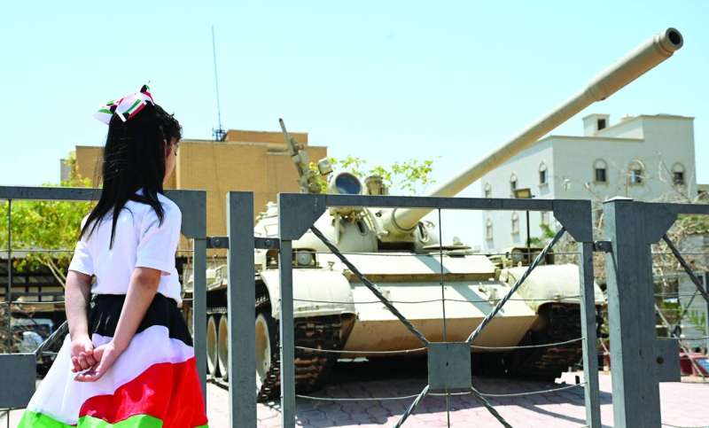 طفلة ترنو إلى دبابة من زمن الغزو 