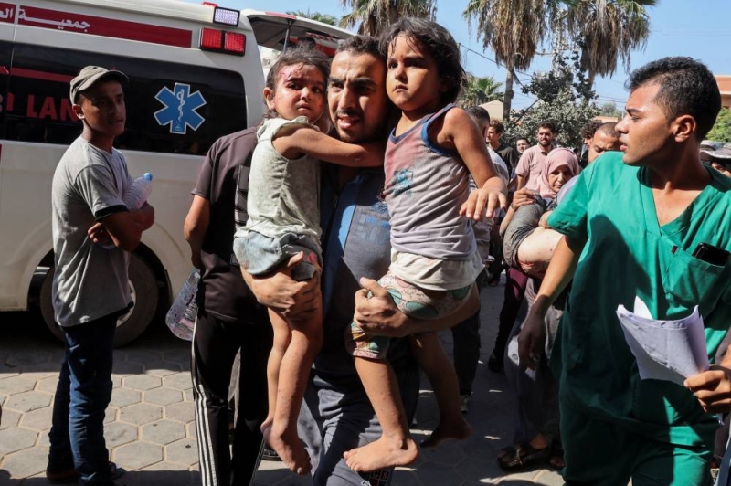 فلسطيني ينقل طفلتيه المصابتين إلى المستشفى بعد غارة إسرائيلية على غزة (رويترز)