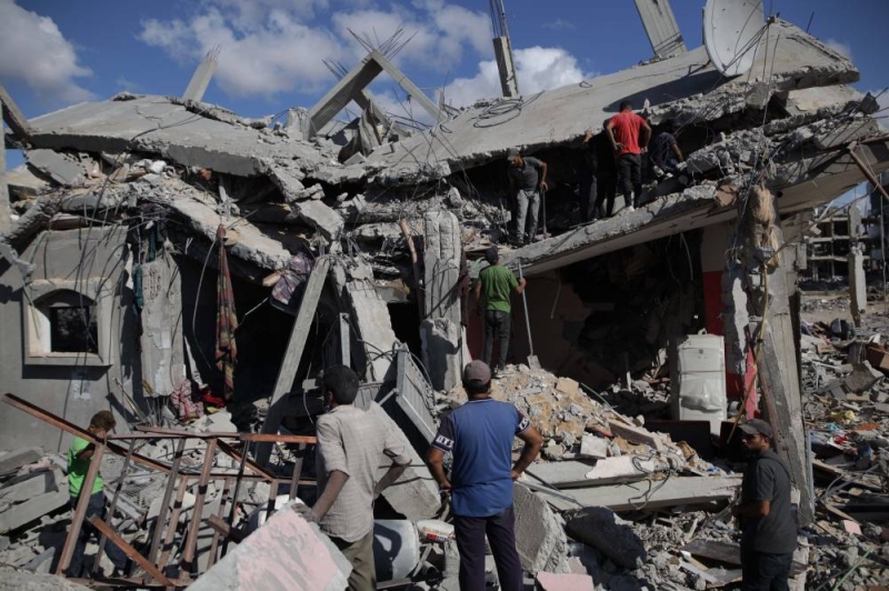 فلسطينيون يتفقدون المباني المدمرة في مخيم البريج للاجئين (شينخوا)