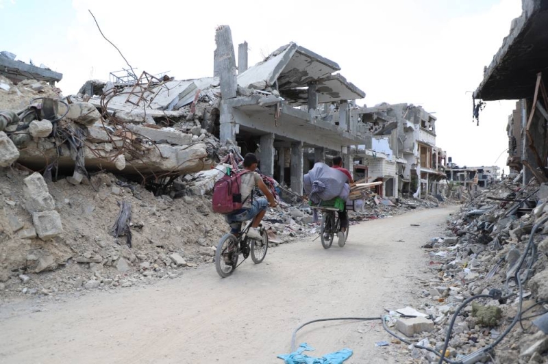 فلسطينيان يسيران وسط الدمار في بيت حانون شمال غزة (شينخوا)