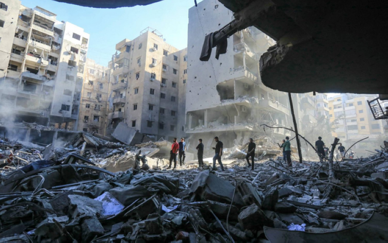 أشخاص يسيرون وسط أنقاض مبان دمرتها الضربة الإسرائيلية على مقر «حزب الله» في الضاحية الجنوبية لبيروت (أ ف ب)