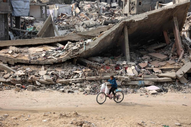 طفل فلسطيني يركب دراجته قرب مبنى مدمر في شمال غزة (أ ف ب)