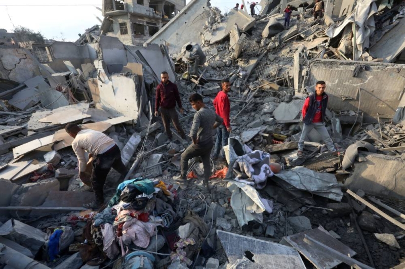 فلسطينيون يتفقدون موقع غارة إسرائيلية في مخيم النصيرات وسط غزة (رويترز)