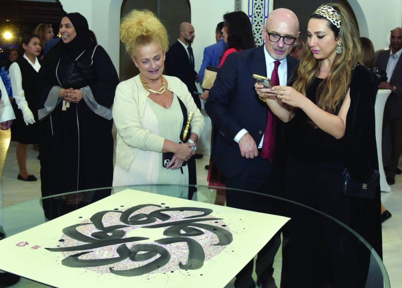 السفير موريني أمام لوحة مع ضيفتين في الفعالية