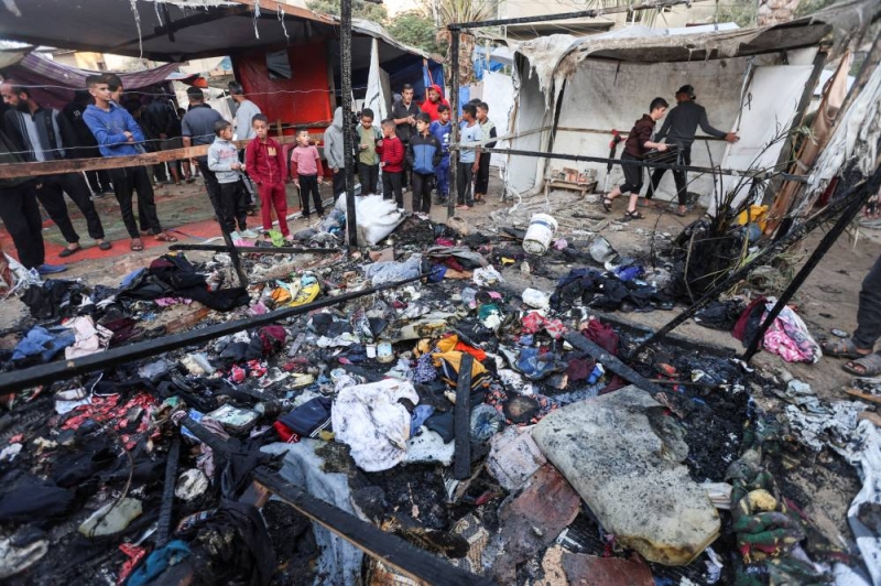 فلسطينيون يتفقدون موقع غارة إسرائيلية على خيام النازحين في ديرالبلح (رويترز)