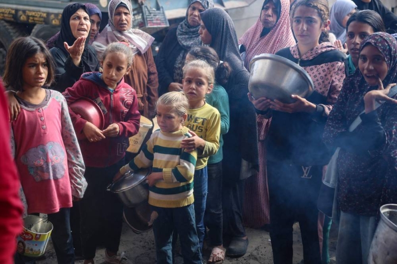 فلسطينيون ينتظرون الحصول على طعام في مخيم البريج (أ ف ب)