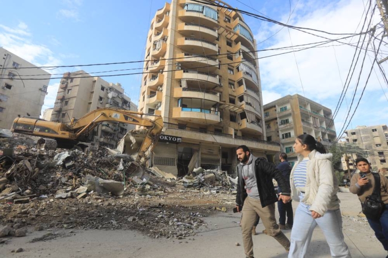 لبنانيون يسيرون قرب مبانٍ مدمرة في الضاحية الجنوبية لبيروت (شينخوا)