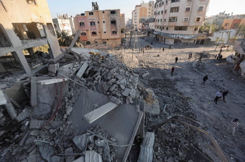 فلسطينيون يتفقدون موقع غارة إسرائيلية في مخيم النصيرات للاجئين وسط غزة (رويترز)