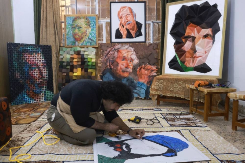 سلوان كريم يعمل على إحدى الرسومات وفي الخلفية لوحات لرموز عراقية وعالمية