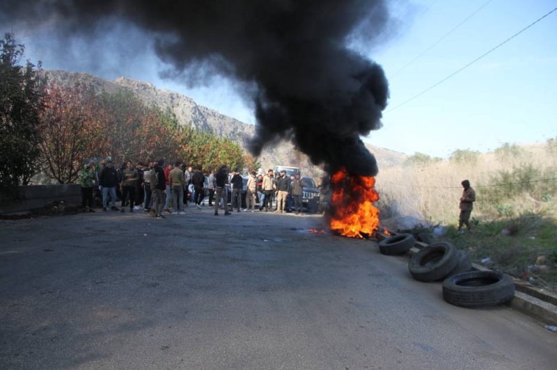 أشخاص يقطعون الطريق احتجاجاً على منعهم من العودة إلى بلدتهم كفرشوبا (شينخوا)