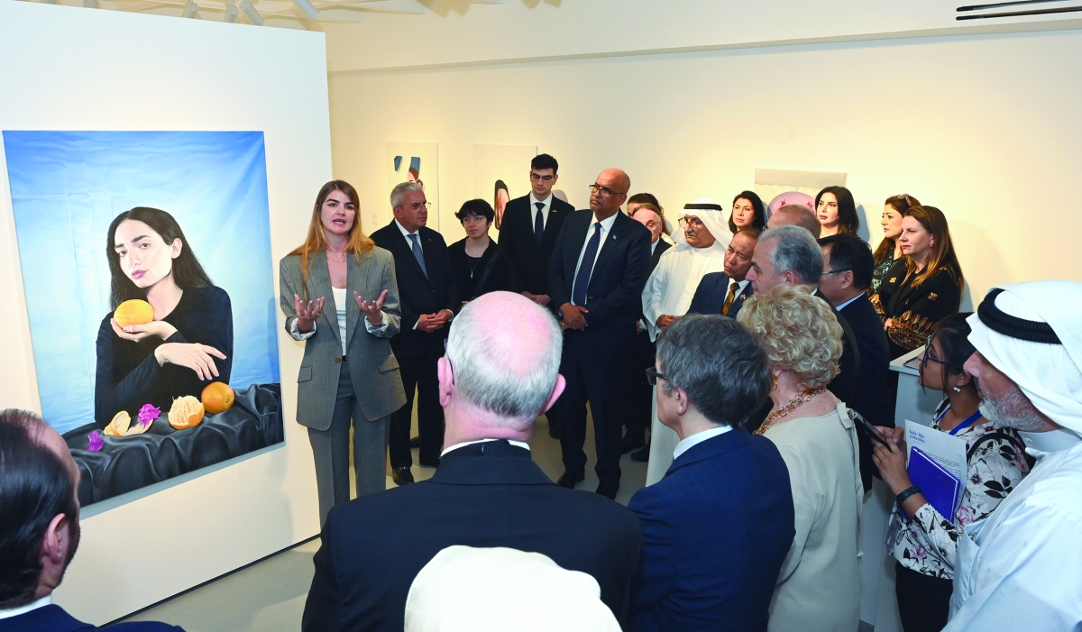 الفنانة ريم زغموت تشرح للحضور لوحة فنية بمشاركة السفير الفلسطيني 	(تصوير سعود سالم) 