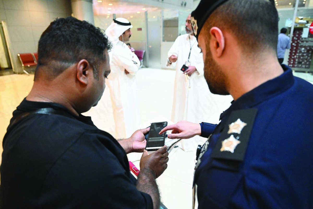 ضابط يُساعد أحد المقيمين لإظهار إذن المغادرة 