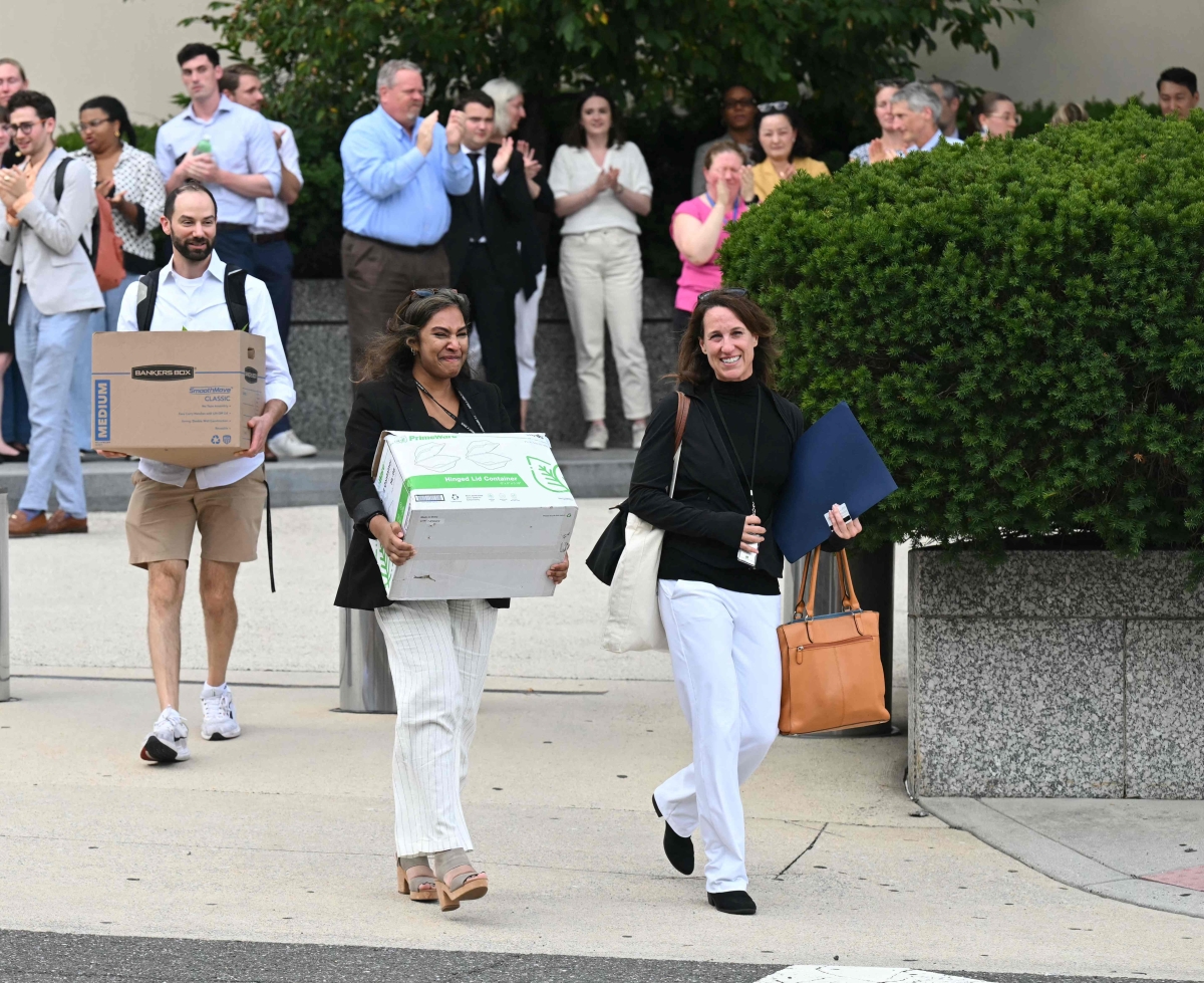 موظفون مُسرحون يحملون أمتعتهم أثناء مغادرتهم مبنى وزارة الخارجية