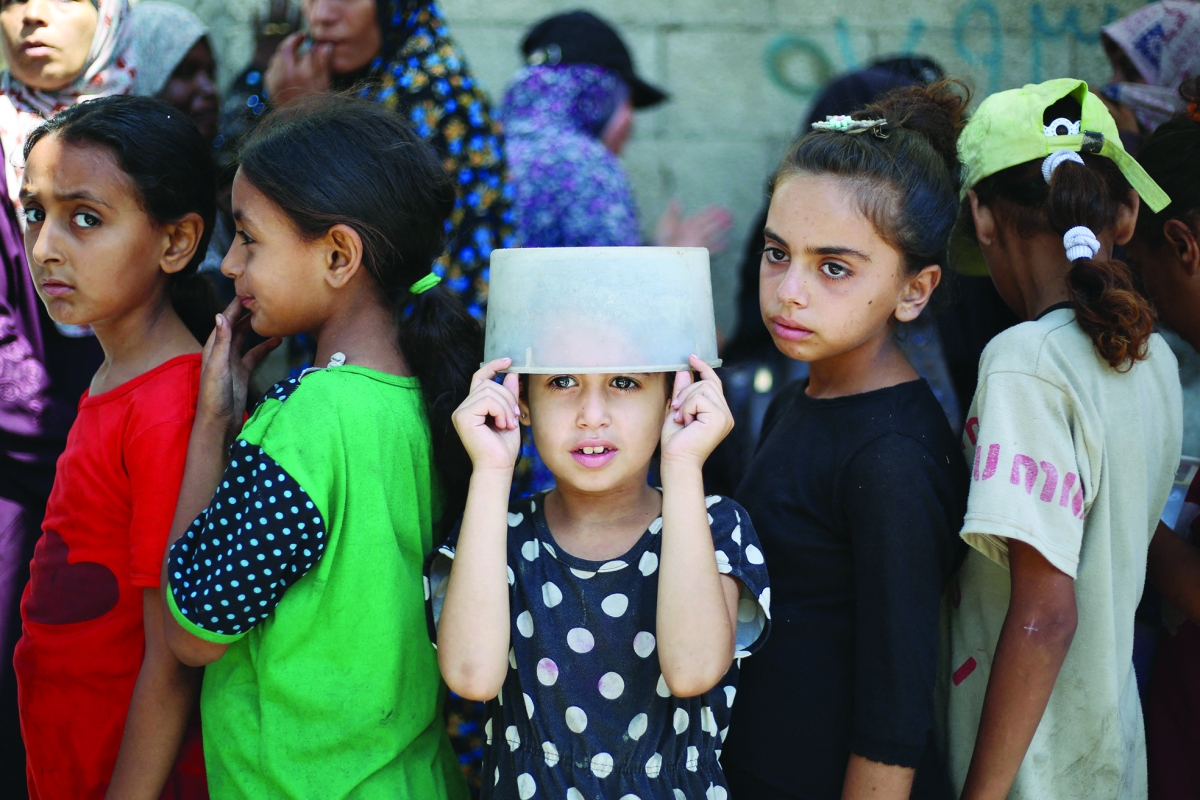 أطفال ينتظرون الحصول على وجبة غذاء في مخيم النصيرات (أ ف ب)