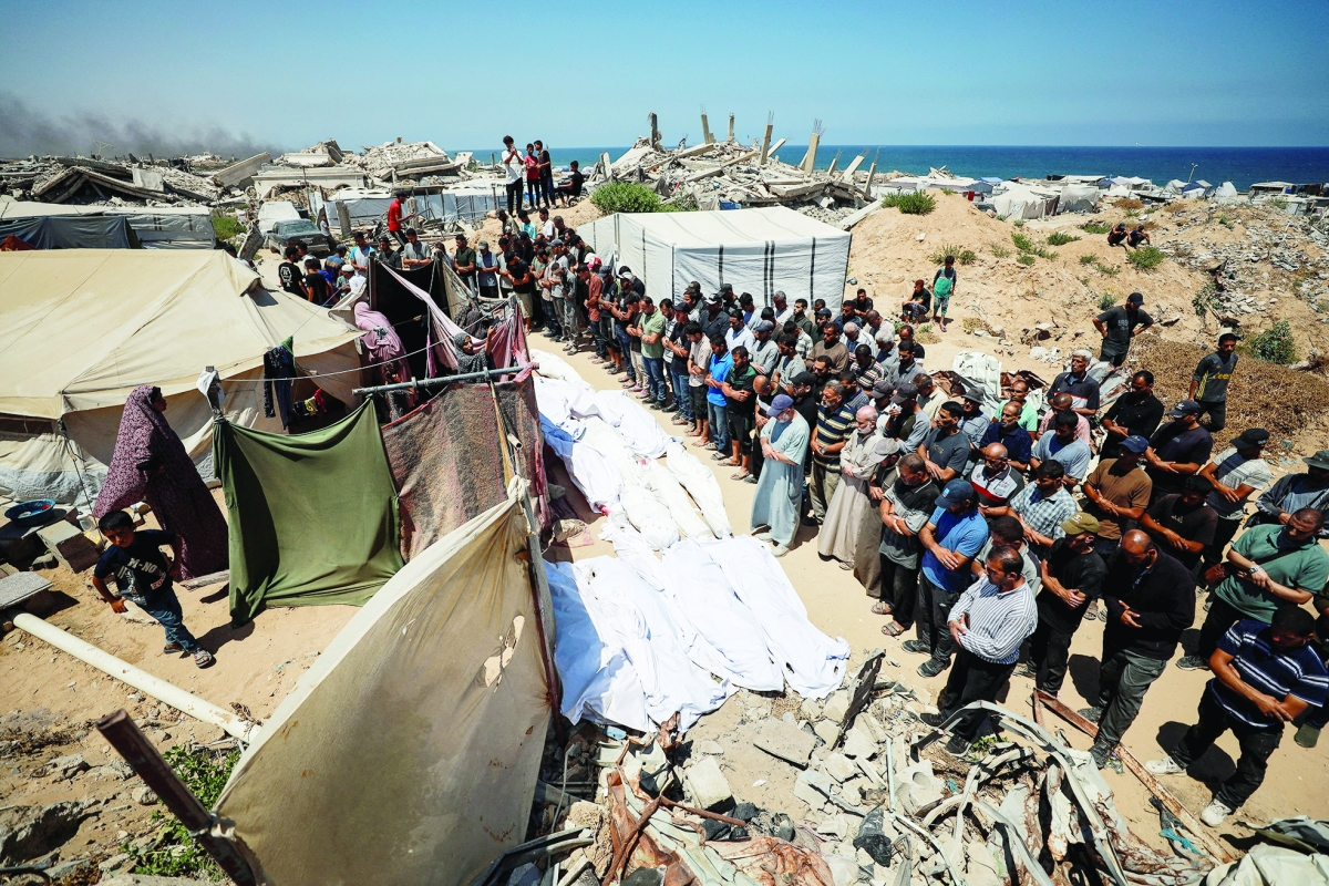 المشيعون يصلون أمام جثث أفراد عائلة عزام الذين استشهدوا في غارة إسرائيلية  (رويترز)