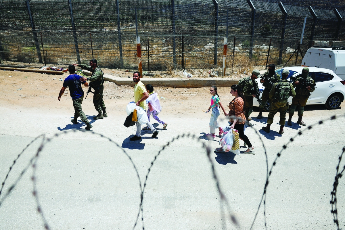 


الجيش الإسرائيلي يرافق مدنيين يعودون سيراً من بلدة مجدل شمس إلى سوريا 	(رويترز) 