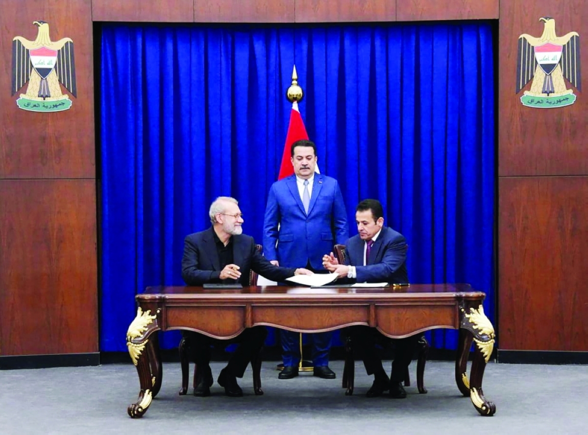 السوداني متوسطاً لاريجاني والأعرجي خلال توقيع مذكرة التفاهم في بغداد (أ ف ب) 