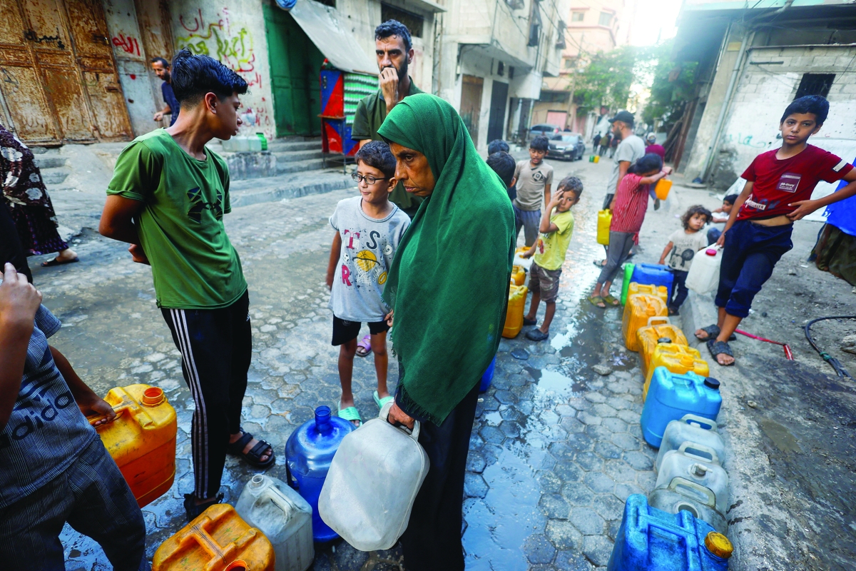فلسطينيون ينتظرون الحصول على المياه في غزة (رويترز)