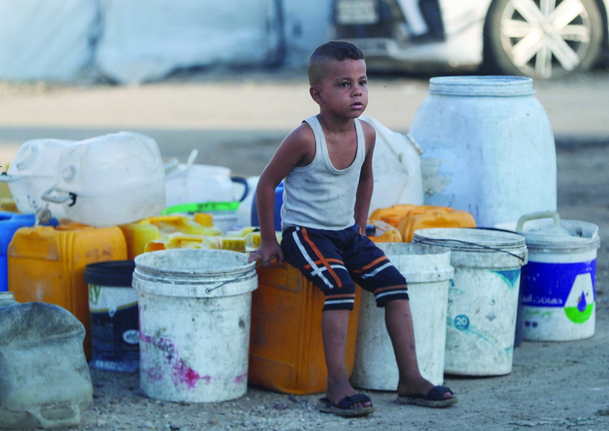 طفل فلسطيني ينتظر الحصول على ماء في غزة (رويترز)