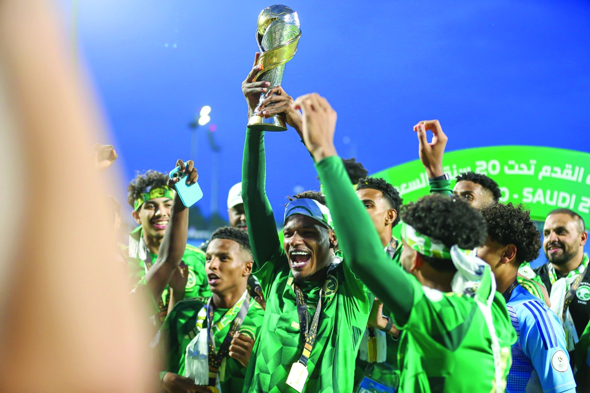 لاعب المنتخب السعودي يرفع كأس البطولة